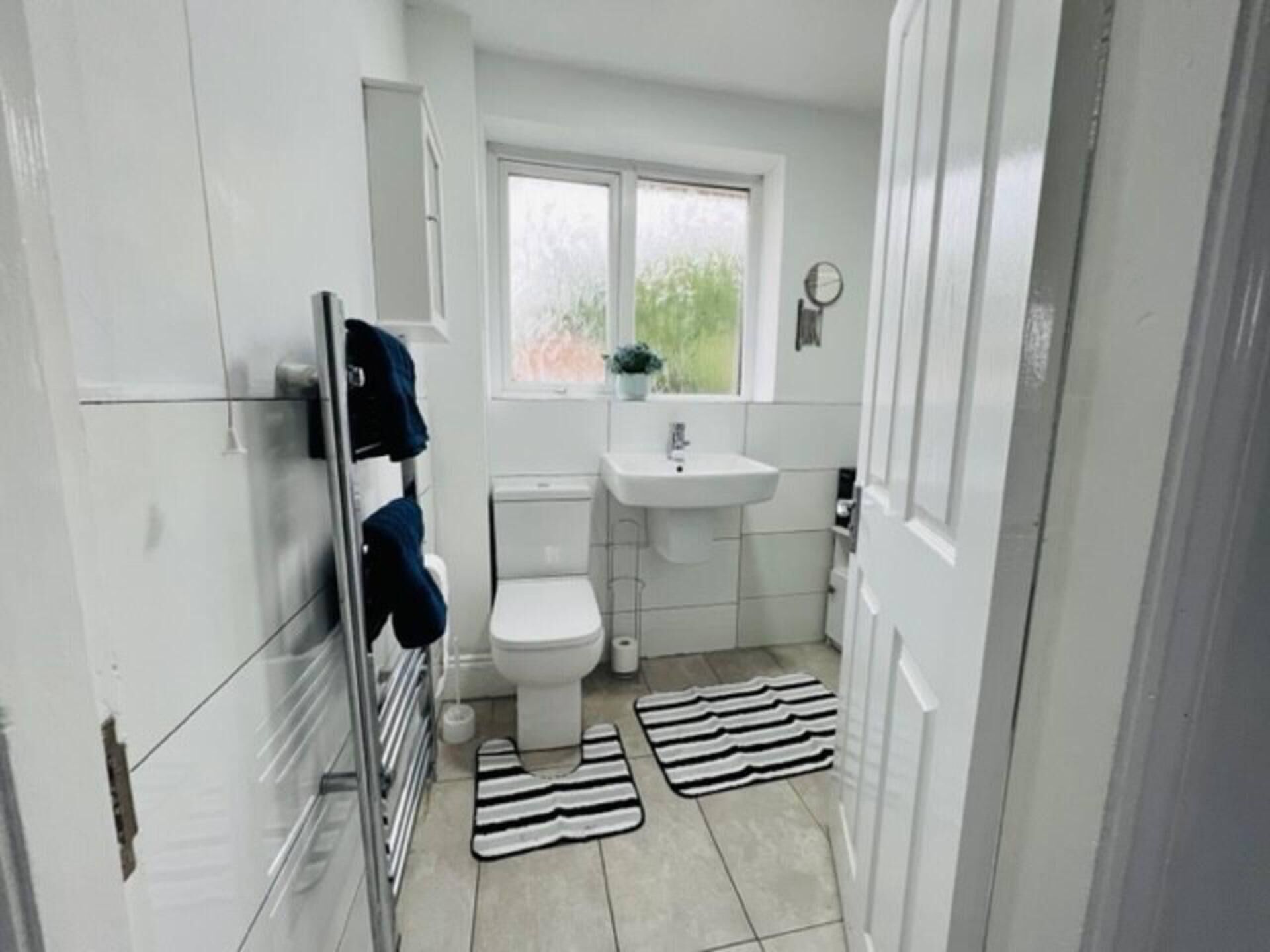 A small, modern bathroom with a toilet, sink, and towel rack.