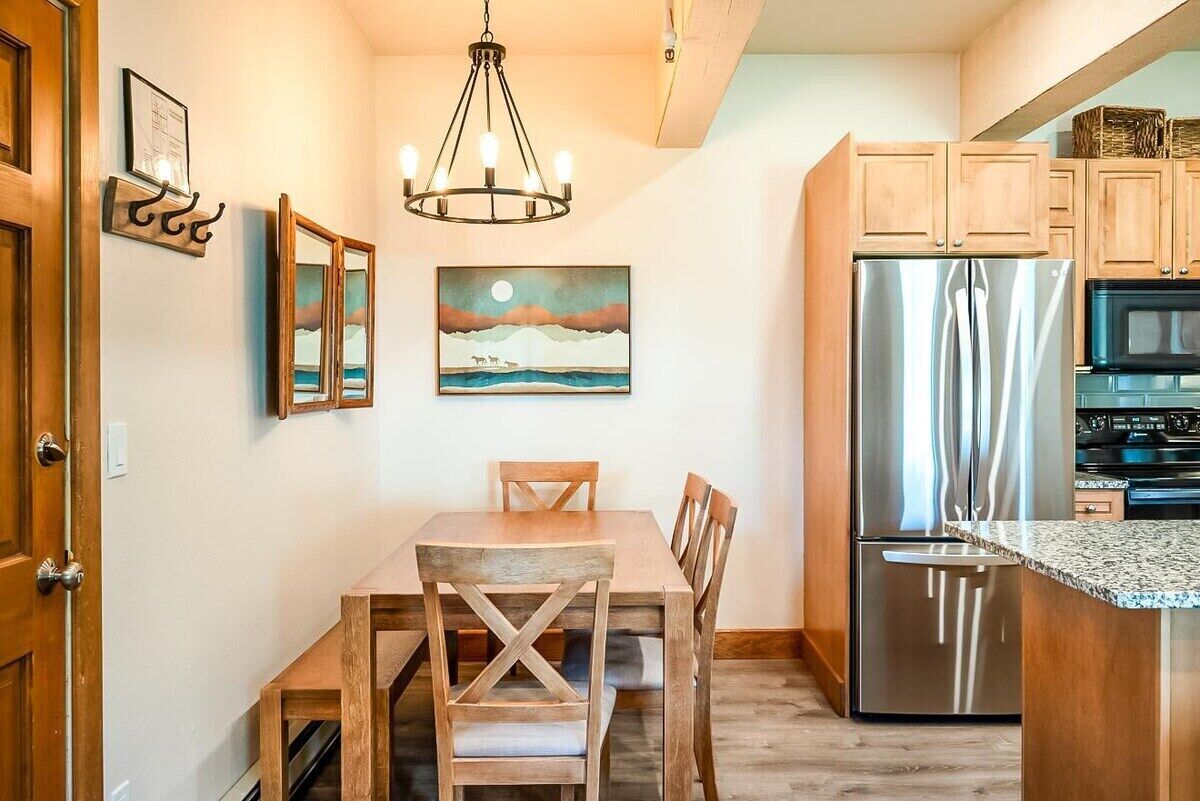 Une cuisine avec des meubles de rangement en bois, un réfrigérateur en acier inoxydable et une table à manger avec des chaises.