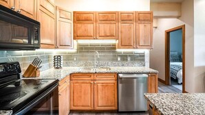 A kitchen with wooden cabinets, a stainless steel dishwasher, and a granite countertop. - Cozy Ketchum Condo  - Walk to Everything! (Ketchum)