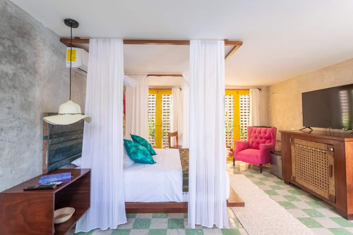 A bedroom with a bed, a television, a chair, and a wooden cabinet.