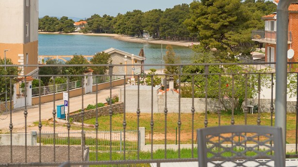 A view of a coastal area with a beach, trees, and buildings. - Apartment at second floor (Pirovac)