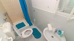 A bathroom with a toilet, bidet, sink, and shower area. - Apartment at second floor (Pirovac)