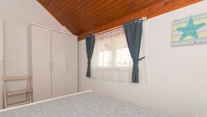 A bedroom with a bed, wardrobe, and a window with curtains. - Apartment at second floor (Pirovac)