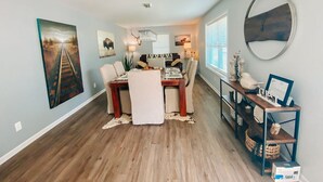 A dining area with a wooden table, chairs, and a chandelier. There are framed pictures on the walls and a round mirror on the wall. - Sisters Four Bed and Bath - Luxury living in a small town atmosphere!   (Centralia)