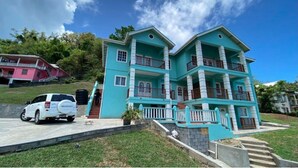 A two-story building with a flat roof, multiple balconies, and a paved driveway. - Golden Palms Two-Bedroom Apartment (Diamond)