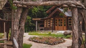 A rustic cabin with a stone pathway leading to it, surrounded by dense forest. - Jela Natural Resort (Rozaje)