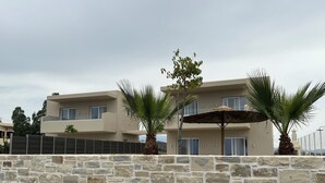 A modern two-story building with a stone wall in the foreground. - Villa Luna 1 with swimming pool in Pitsidia (Pitsidia)