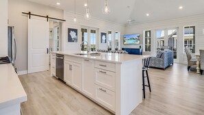A spacious kitchen with a large island, white cabinetry, and pendant lighting.