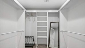 A narrow hallway with white walls and a wooden floor, leading to a room with a bed and a wardrobe. - Luxury New Tranquil Retreat-Walk to Waterfront (Ocean Springs)