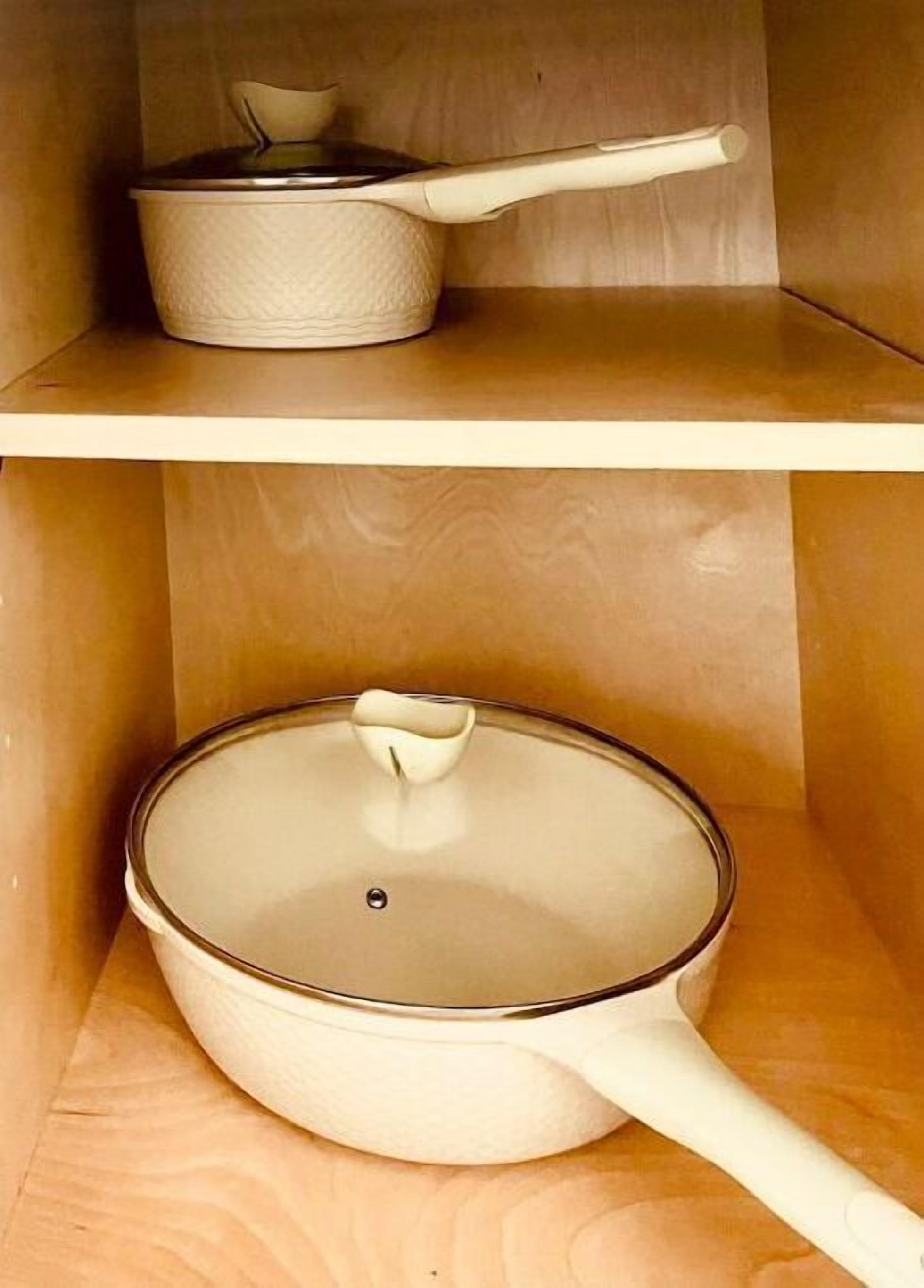 A kitchen with a pot on the upper shelf and a pan on the lower shelf.