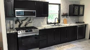Une cuisine moderne avec des meubles de couleur noire, une cuisinière en acier inoxydable, un four à micro-ondes et un évier.