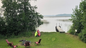 Une zone herbeuse avec une jetée qui s’avance sur un lac paisible, le tout entouré d’arbres.