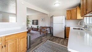 A modern kitchen with wooden cabinets, a refrigerator, and a dining area with a table and chairs. - NO exta fees, Beautiful half duplex 3br, 2ba, w/gym, office and fenced in yard. (Aurora)