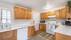 A kitchen with wooden cabinets, a white stove, a microwave, and a sink. - NO exta fees, Beautiful half duplex 3br, 2ba, w/gym, office and fenced in yard. (Aurora)