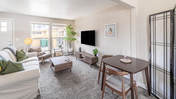 A living room with a sofa, coffee table, TV, and dining area. - NO exta fees, Beautiful half duplex 3br, 2ba, w/gym, office and fenced in yard. (Aurora)