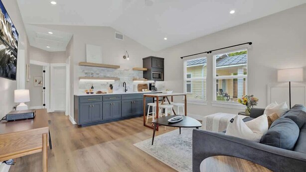 Una cocina moderna con gabinetes grises, una isla central y una zona de comedor con mesa y sillas.