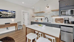 Una cocina moderna con una isla grande, electrodomésticos integrados y una zona de comedor con taburetes de bar.