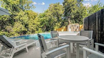 Zona junto a la piscina con sillones, una mesa y una valla de madera.