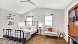 Una camera da letto con un letto, un divano, un tavolino e una ventola a soffitto.