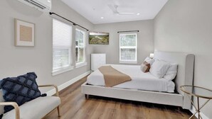 Een moderne slaapkamer met een bed, nachtkastjes, een stoel en een klein tafeltje.