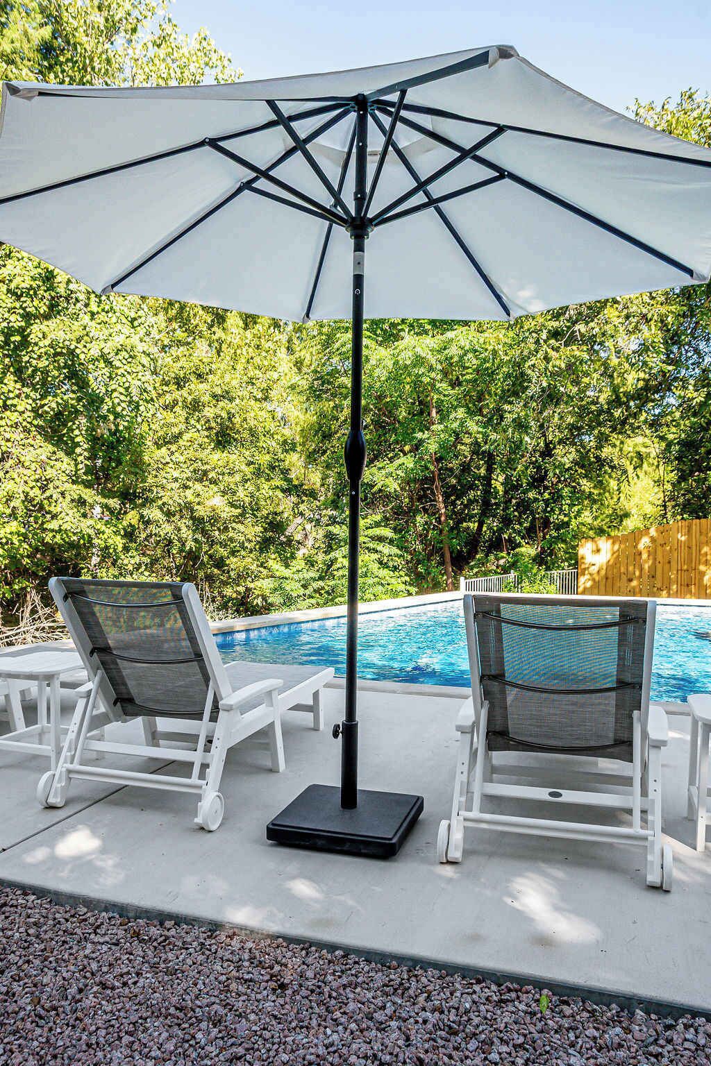 A poolside area with two lounge chairs and a large umbrella.