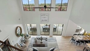 A spacious living area with a high ceiling, large windows, and a central seating area with a coffee table. - The Point Serene Hill Country Views With Pool & Hot Tub (Fredericksburg)