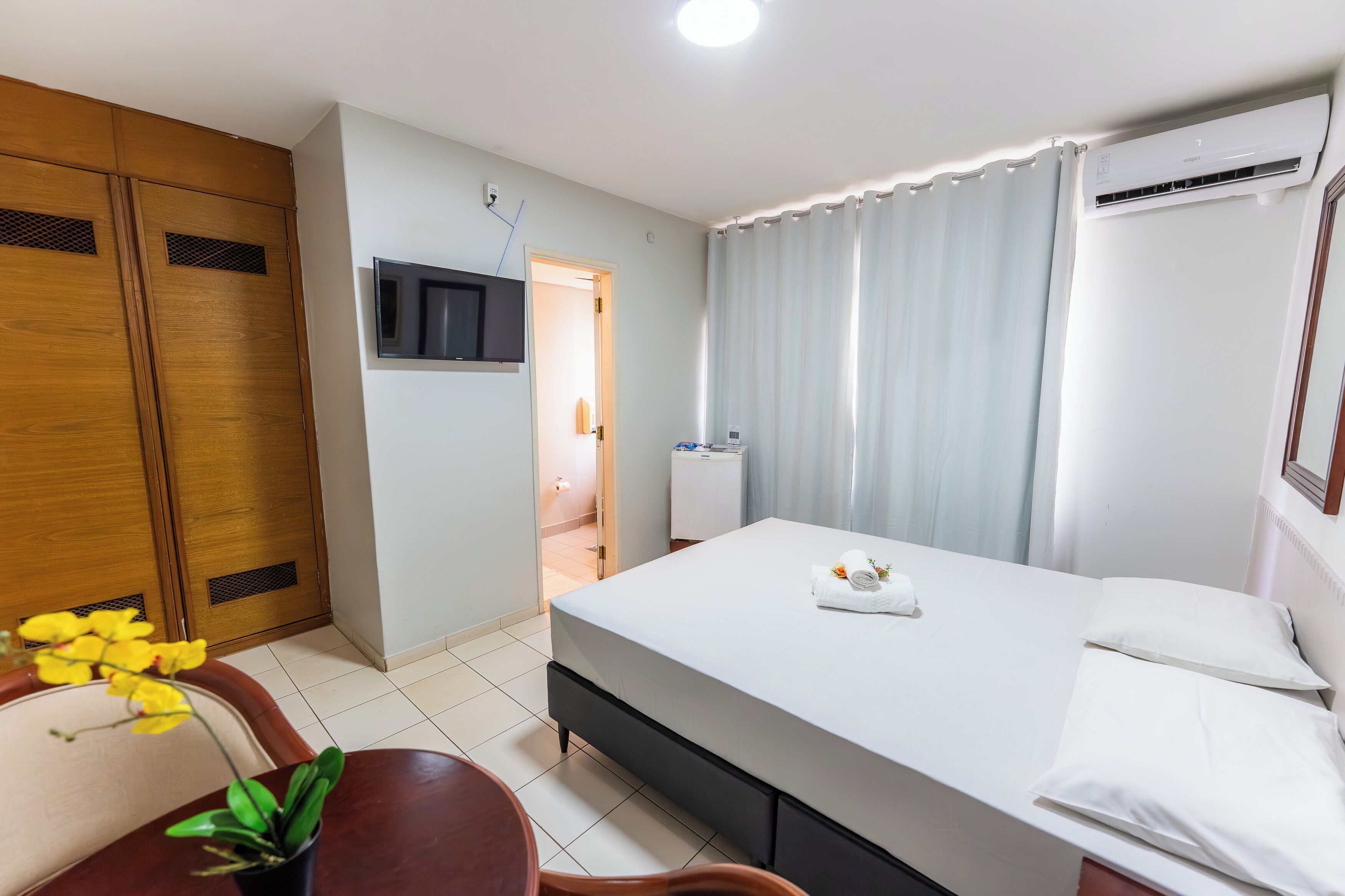 A hotel room with a bed, a TV, a desk, and a chair.