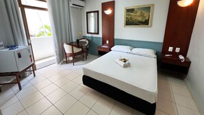 A hotel room with a bed, a desk, a chair, a desk lamp, a nightstand, a wall-mounted mirror, and a painting. - Hotel Alvorada by Bsb Inn (Taguatinga)