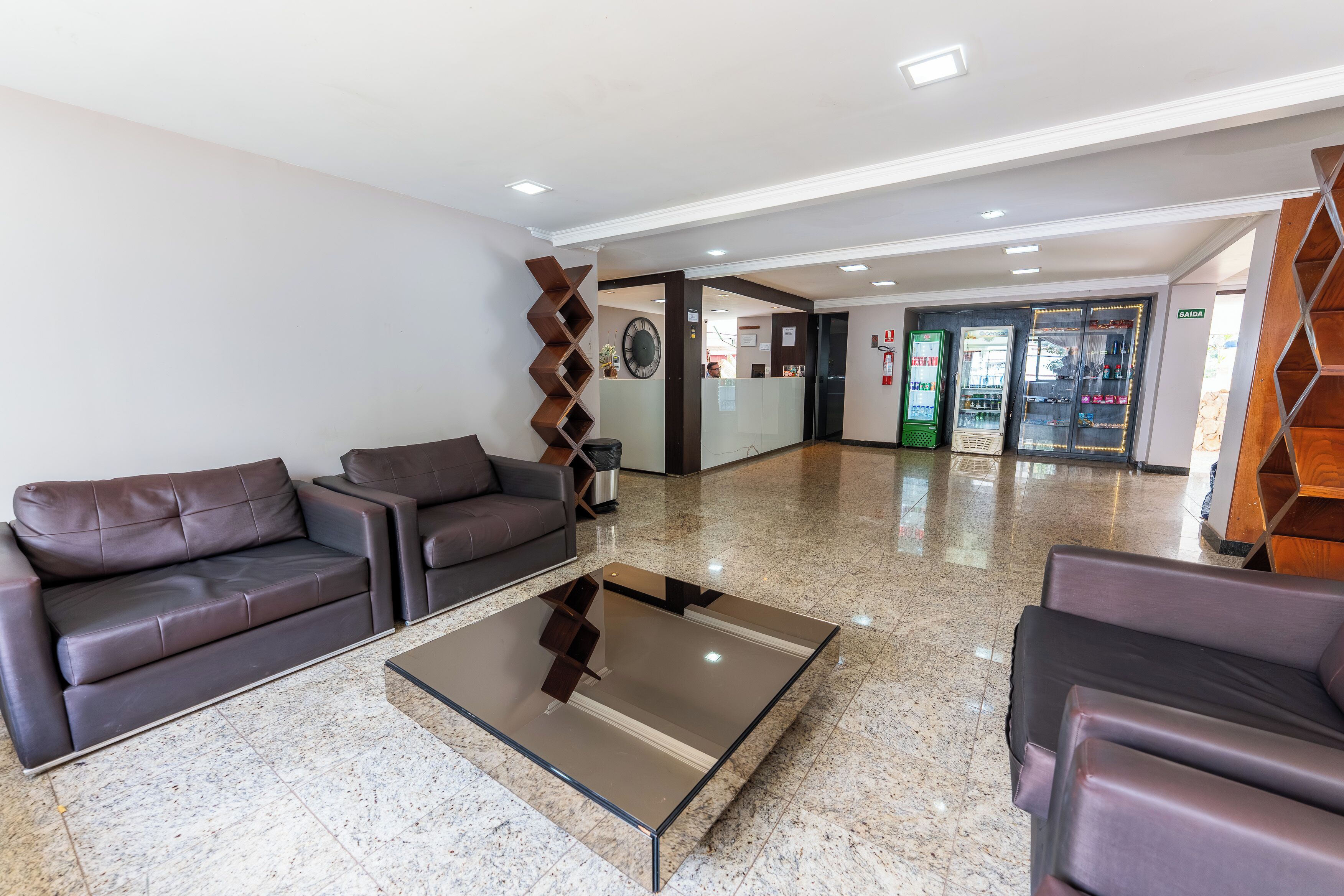 A lobby with leather sofas, a glass coffee table, a clock, and a reception desk.