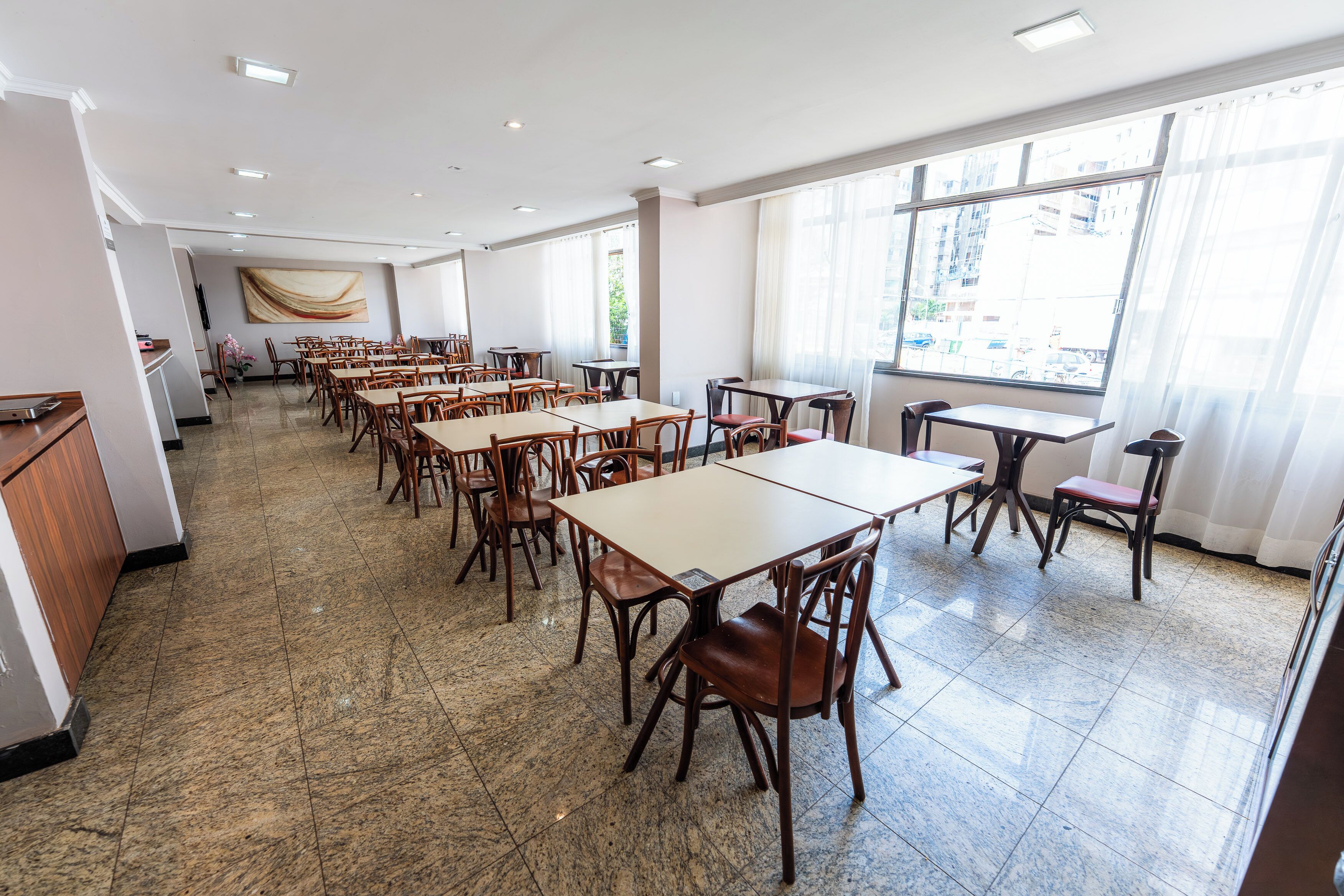 Un comedor amplio con varias mesas y sillas, ventanas grandes y un diseño de interiores moderno.