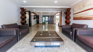 A modern lobby with a central seating area, a glass door entrance, and a large abstract painting on the wall. - Hotel Alvorada by Bsb Inn (Taguatinga)