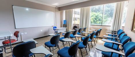 A classroom with rows of blue chairs, a whiteboard, and a projector.