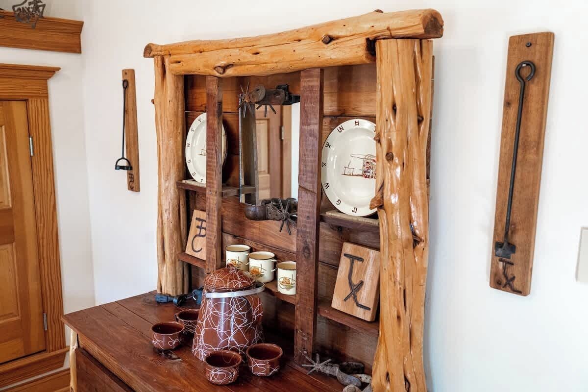 Une étagère en bois rustique, ornée d’assiettes, de tasses et d’un grand pot en céramique.