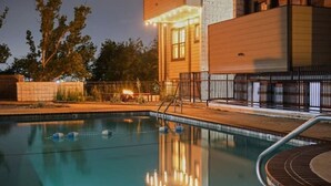 Une piscine dotée d’une terrasse en bois et d’une rambarde en métal.