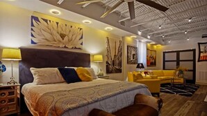 Une chambre d’hôtel moderne avec un grand lit, un canapé jaune et un banc en bois.