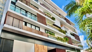 A modern multi-story hotel with balconies, large windows, and a wooden facade. - Kuxtal 3 Bedroom Downtown Apartment  (Playa del Carmen)
