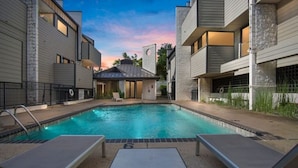 A modern outdoor pool area with lounge chairs and a small gazebo. - Magical Condo in Midtown! (Oklahoma City)