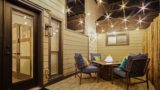 An outdoor patio with a table and chairs, a door, and string lights. - Magical Condo in Midtown! (Oklahoma City)