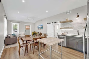 Una cocina moderna con zona de comedor, muebles de madera y salpicadero de piedra.