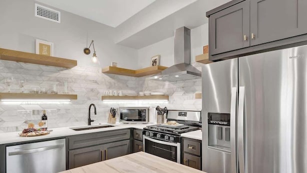 A modern kitchen with a stainless steel refrigerator, a built-in oven, and a microwave. - The Grove-a Charming Cottage - 2 Blks to Main St (Fredericksburg)
