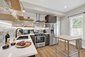 A modern kitchen with a central island, stainless steel appliances, and a window with blinds.