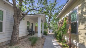 A covered patio area with outdoor seating, a tree, and a pathway leading to a house. - The Grove E With Hot Tub & King Bed - 2 Blks to Main (Fredericksburg)