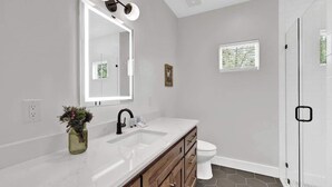 A modern bathroom with a white vanity, a large mirror, and a shower area.