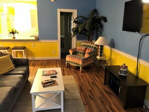 Relax in this inviting living room with a comfortable sofa, plaid armchair, and flat-screen TV.
