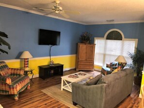 Relax in this cozy space with a ceiling fan, flat-screen TV, and comfortable sofa.