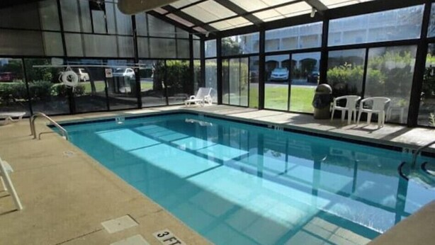 An indoor swimming pool with clear glass walls, a 3 FT depth marking, and a patio area with chairs. - Gorgeous 1st Floor Condo at Arrowhead Country Club
 (Myrtle Beach)