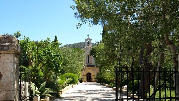 A pathway leading to a church with a bell tower, surrounded by greenery and stone walls. - Villa Camarasa by Balearic Villas (Pollensa)