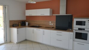 Eine moderne Küche mit weißen Schränken, einer Mikrowelle, einem Backofen und einem Spülbecken.