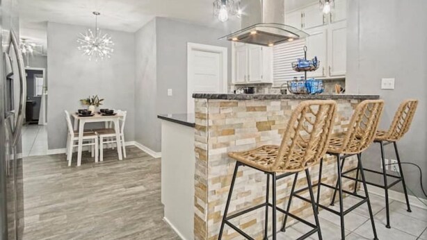 A modern kitchen with a central island, bar stools, and pendant lighting.