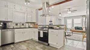 A modern kitchen with white cabinets, a stainless steel dishwasher, and a black stove.